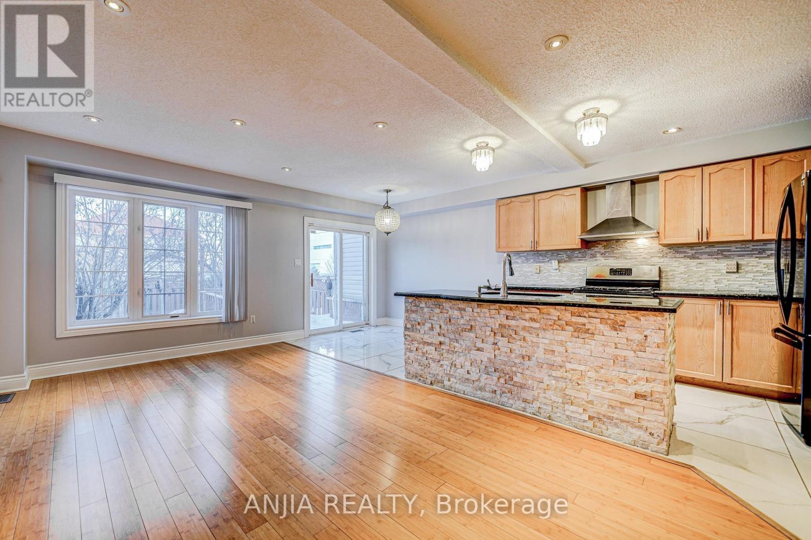 A spacious kitchen with wooden cabinets and a stone backsplash.