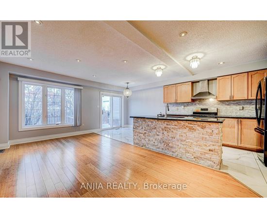 A spacious kitchen with wooden cabinets and a stone backsplash.