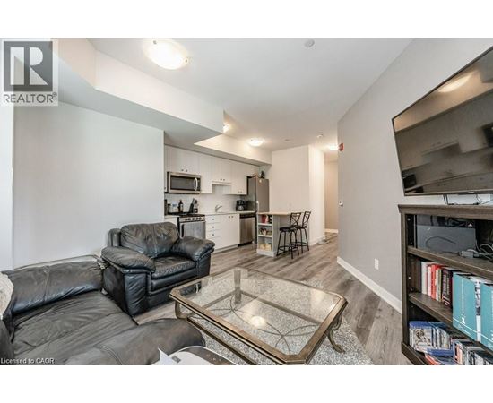 A living room with a black leather couch and a glass coffee table.
