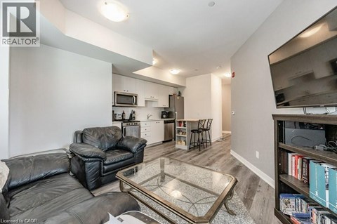 A living room with a black leather couch and a glass coffee table.