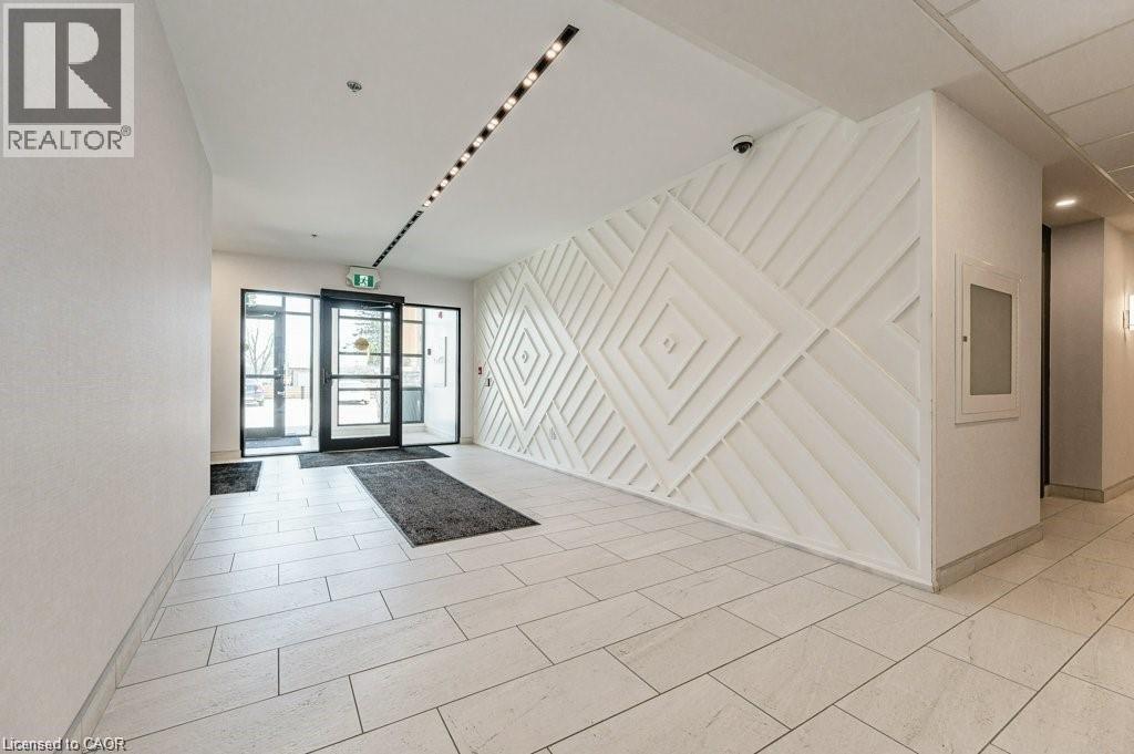A hallway with a white wall and a black and white rug.