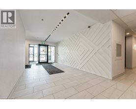 A hallway with a white wall and a black and white rug.