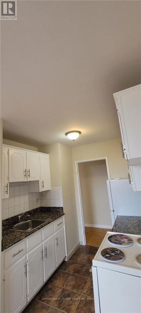 A kitchen with white cabinets and a black countertop.