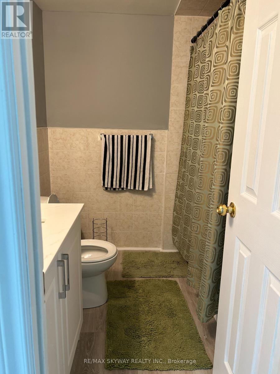 A bathroom with a toilet, a shower curtain, and a green rug.