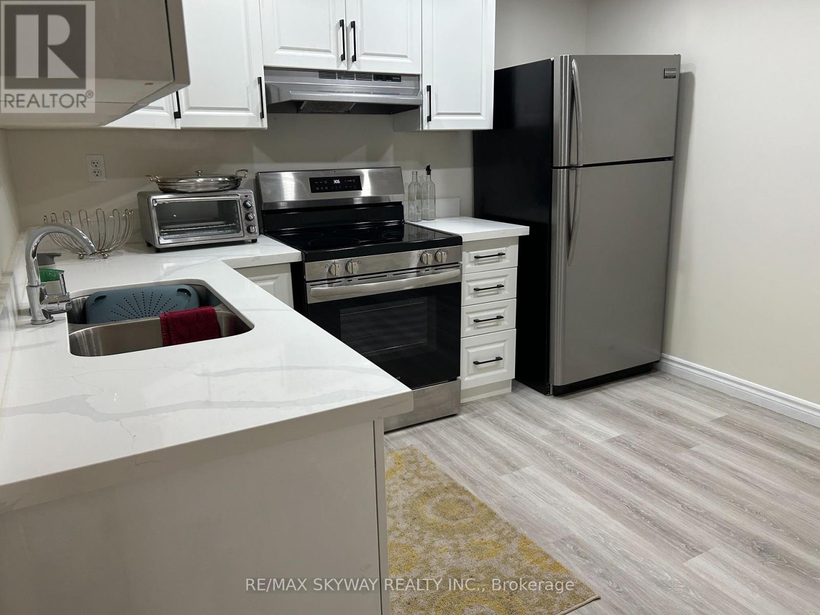 A kitchen with a white counter top and a black refrigerator.