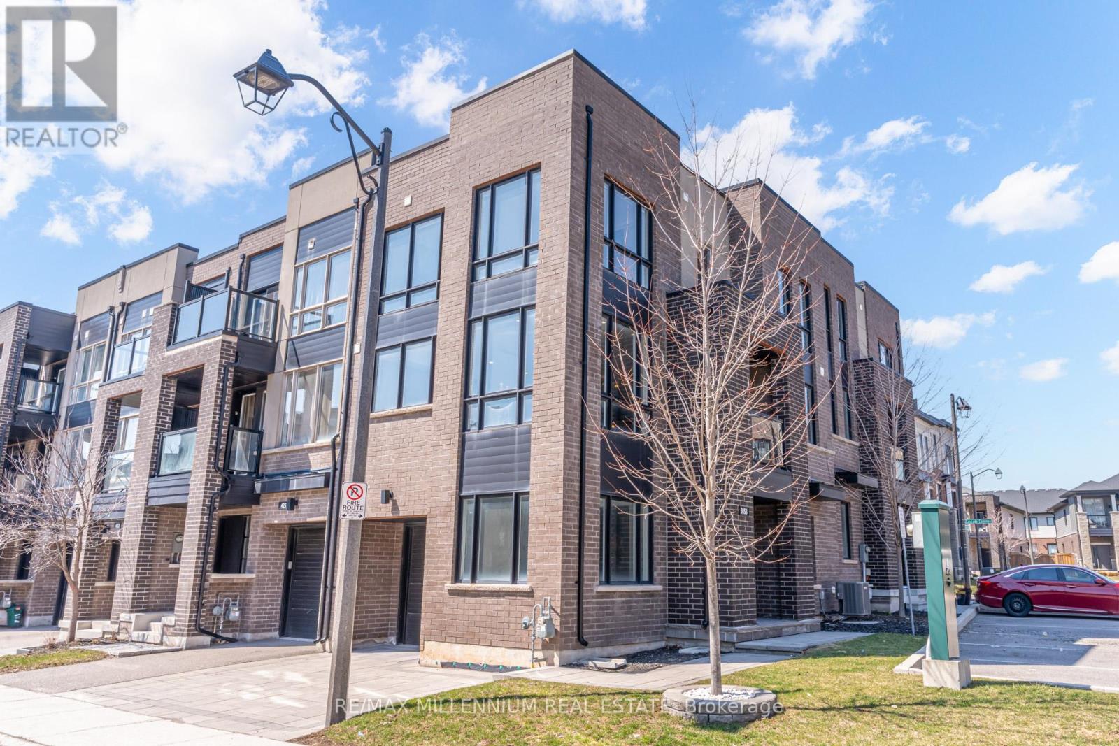 A modern brick building with a sign that reads "RE/MAX Millennium Real Estate" in front of it.