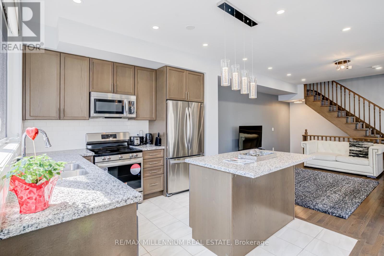 A modern kitchen with a stainless steel refrigerator and a white island.