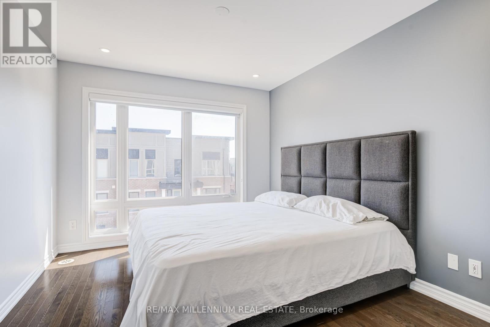 A bedroom with a large bed and a window overlooking a cityscape.