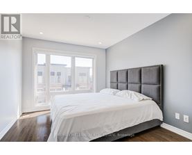A bedroom with a large bed and a window overlooking a cityscape.