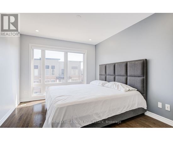 A bedroom with a large bed and a window overlooking a cityscape.