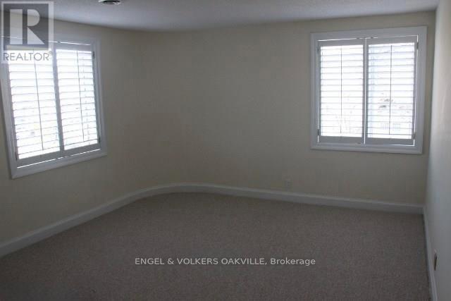 A room with a carpet floor and two windows.