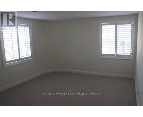 A room with a carpet floor and two windows.