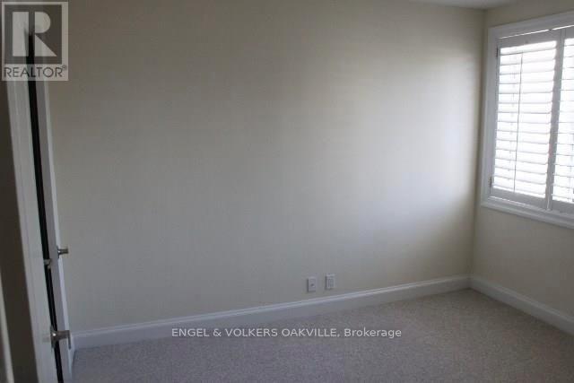 A room with a carpet floor and a window with blinds.