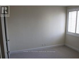 A room with a carpet floor and a window with blinds.