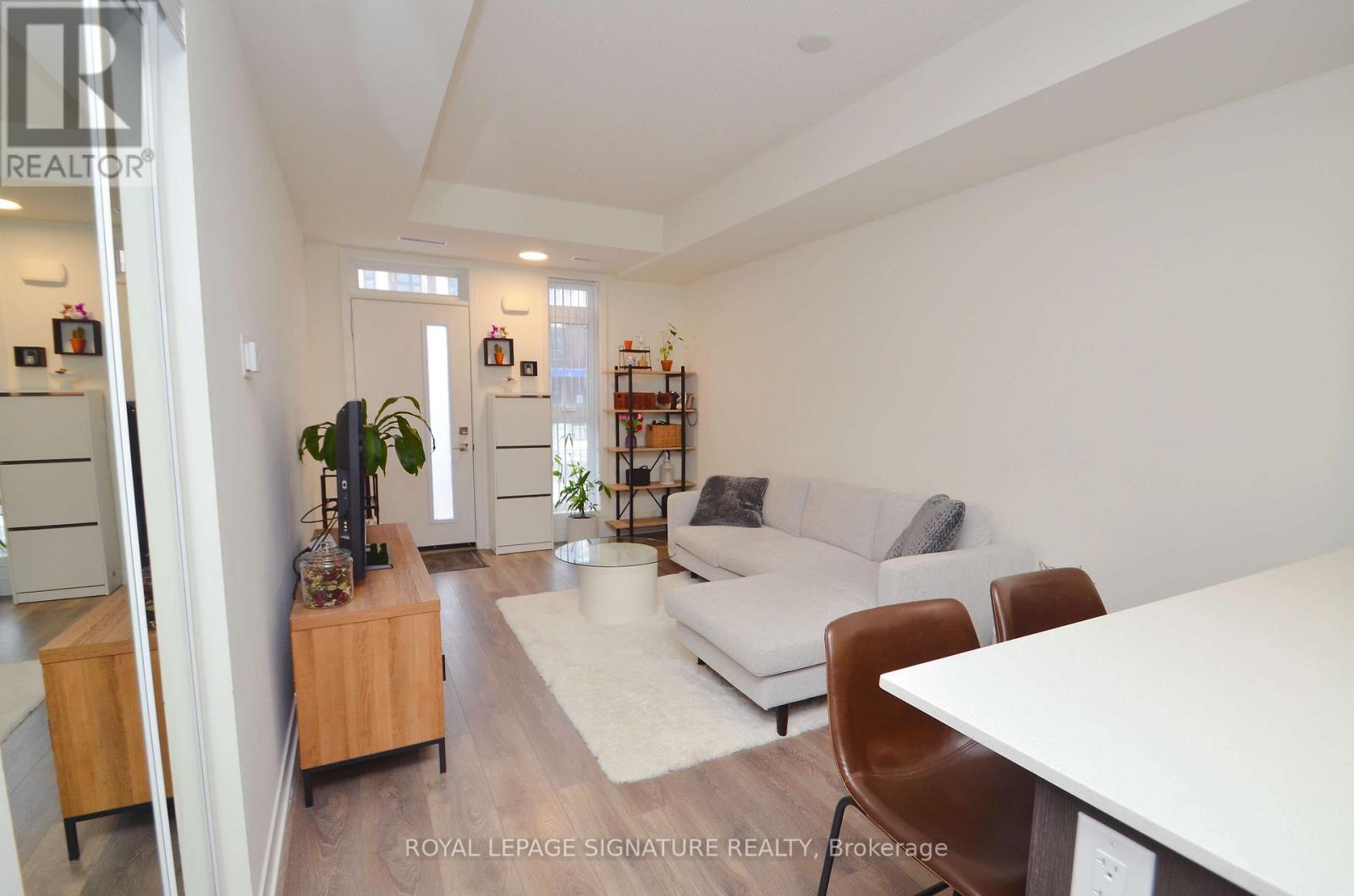 A living room with a white couch, a wooden cabinet, and a white dining table.