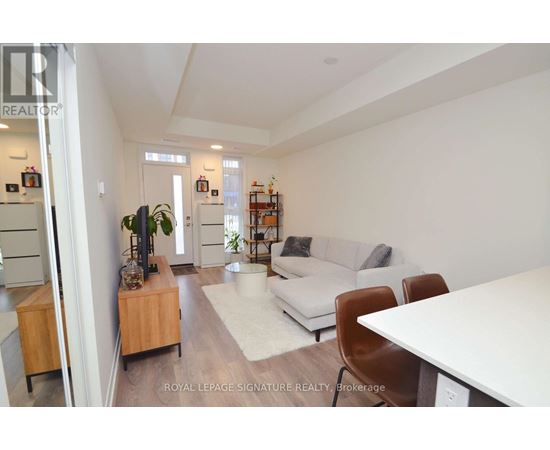 A living room with a white couch, a wooden cabinet, and a white dining table.