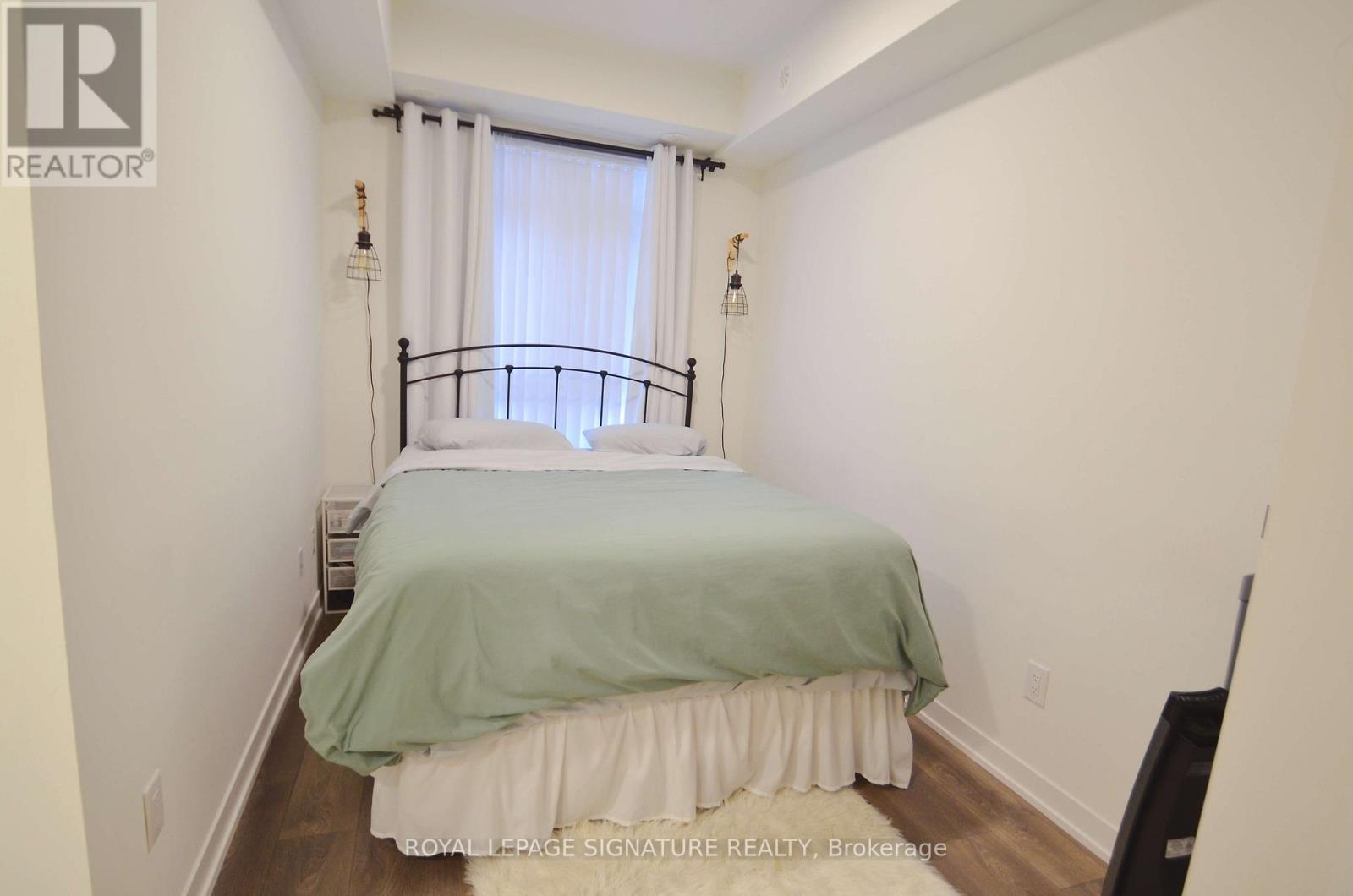 A bedroom with a bed covered in a green and white bedspread.