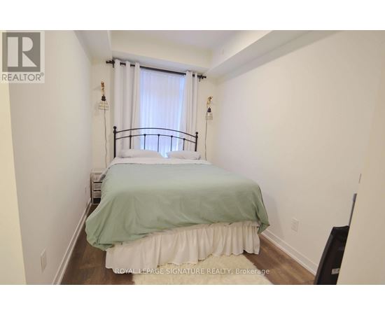 A bedroom with a bed covered in a green and white bedspread.