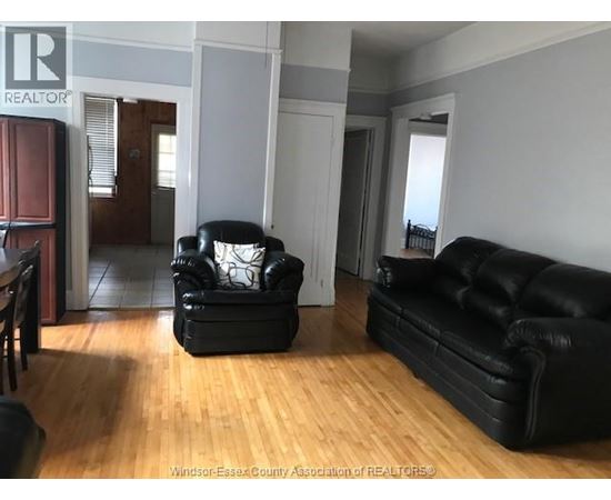 A living room with a black leather couch and chair.