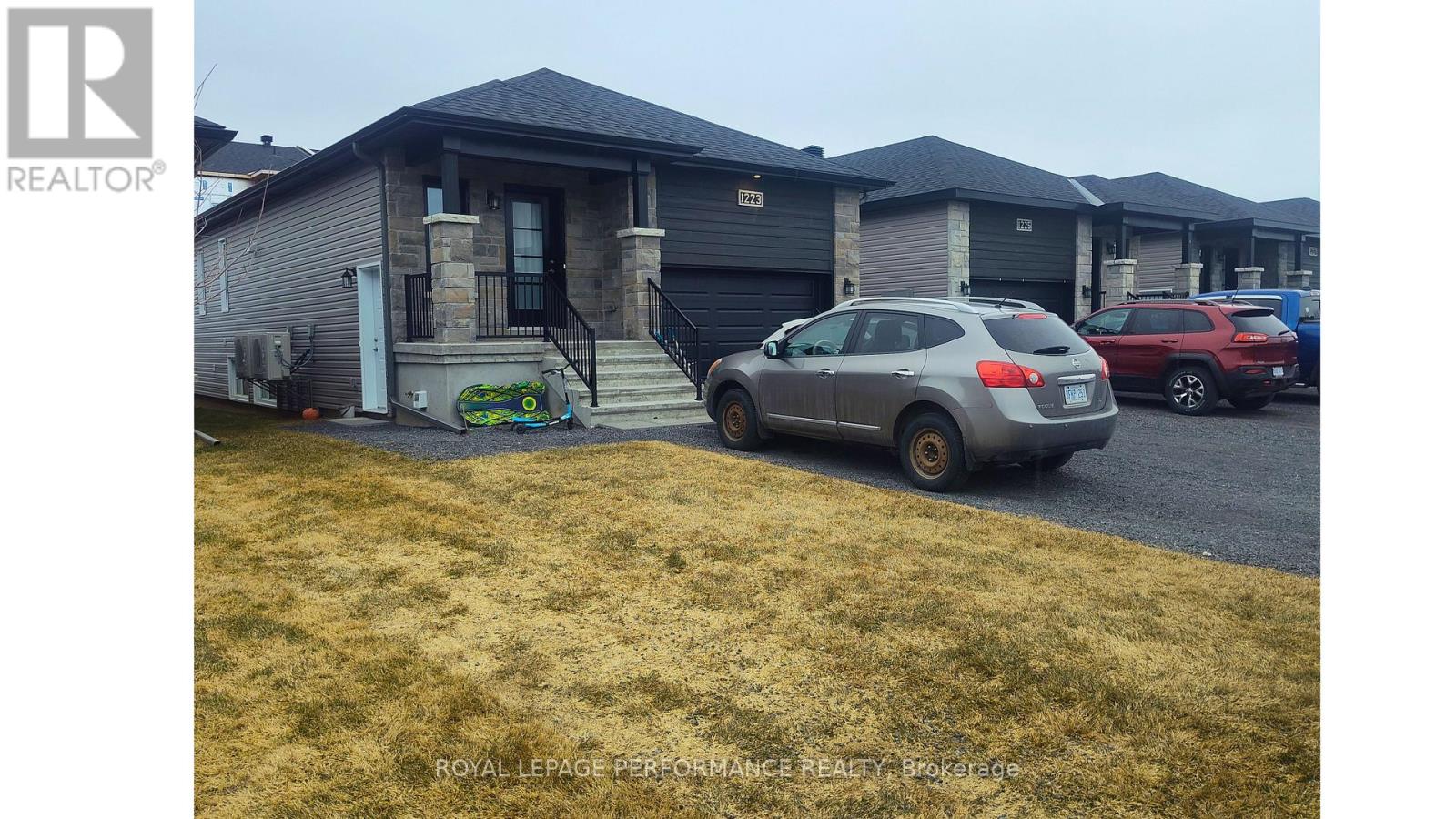 A grey car is parked in front of a house with a sign that says "REALTOR".