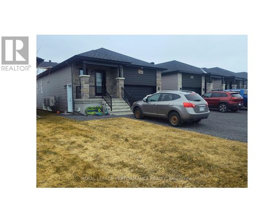 A grey car is parked in front of a house with a sign that says "REALTOR".