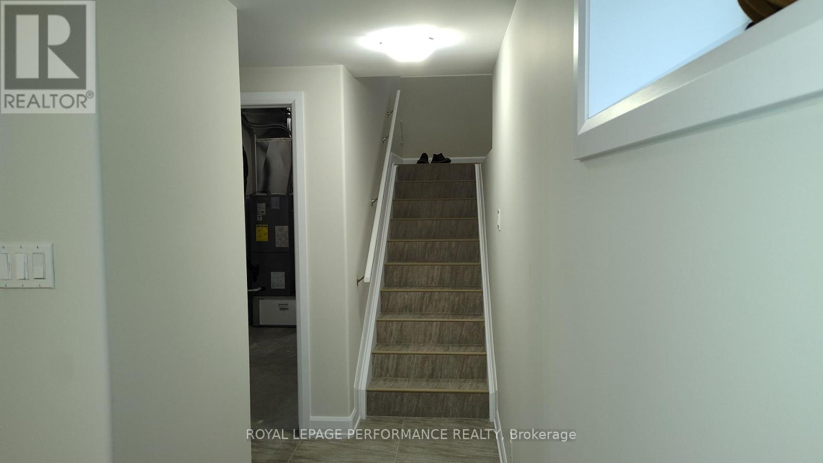 A staircase in a house with a brokerage logo on the wall.