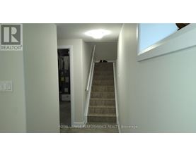 A staircase in a house with a brokerage logo on the wall.