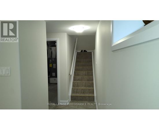 A staircase in a house with a brokerage logo on the wall.