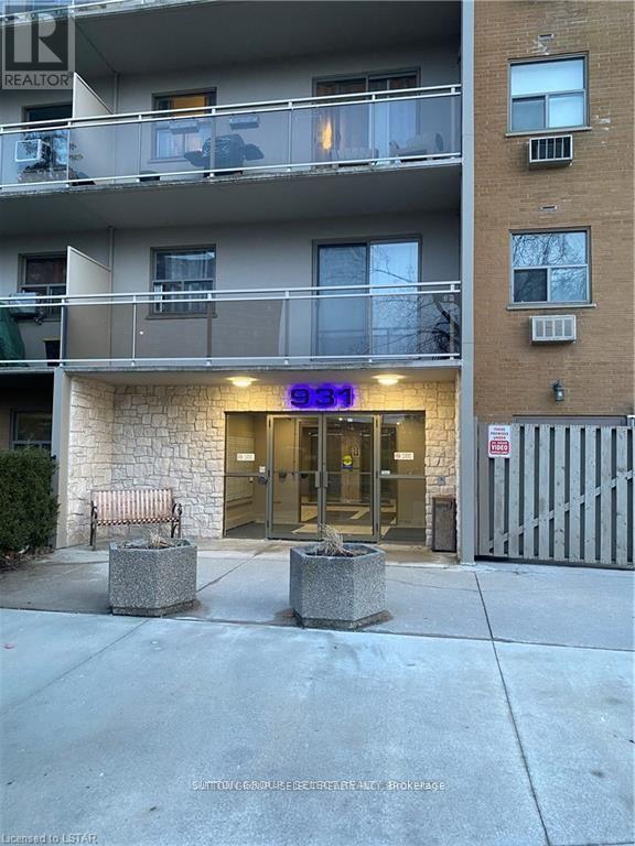 The image shows a building with a stone facade and a balcony on the second floor.