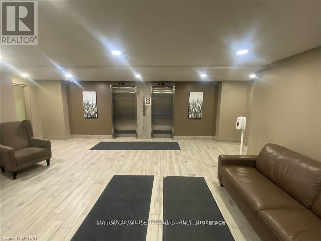 A spacious room with a brown leather couch, a chair, and a rug in the middle.