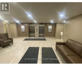 A spacious room with a brown leather couch, a chair, and a rug in the middle.