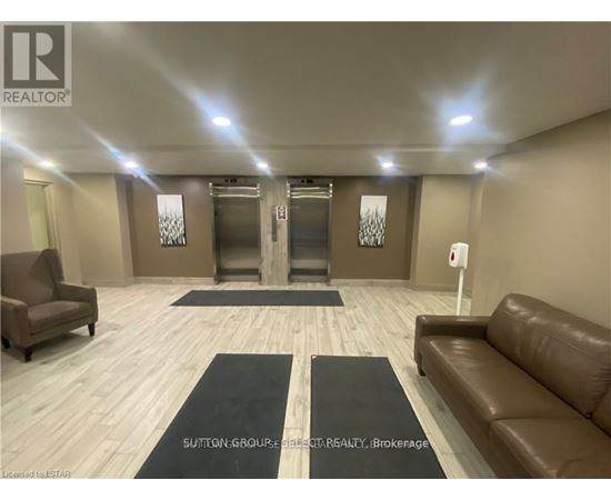 A spacious room with a brown leather couch, a chair, and a rug in the middle.