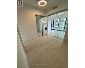 A spacious room with wooden flooring and a glass door leading to a balcony.