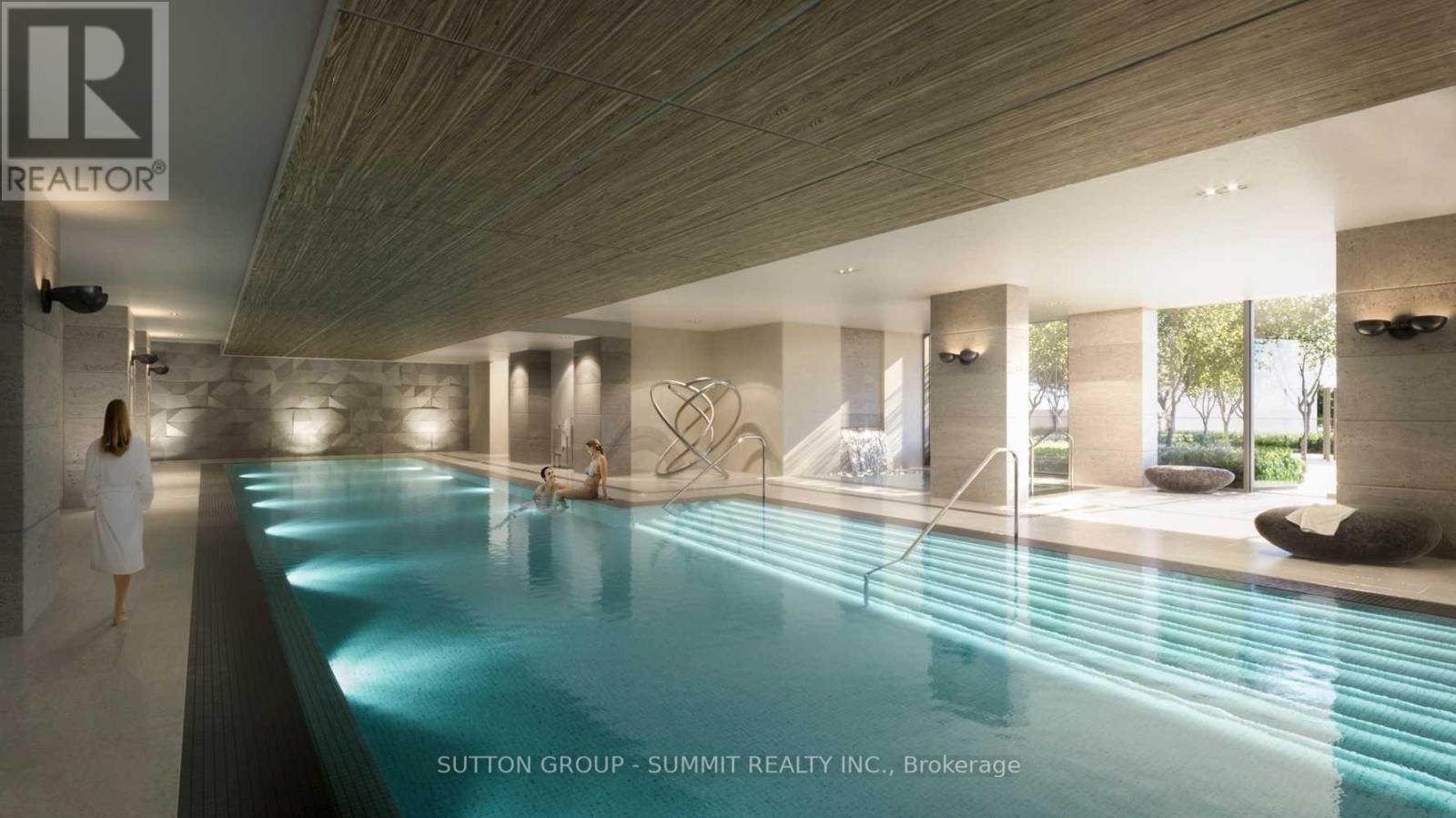 A woman in a white robe is walking through a spacious indoor swimming pool area.