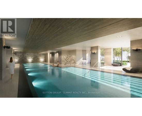 A woman in a white robe is walking through a spacious indoor swimming pool area.