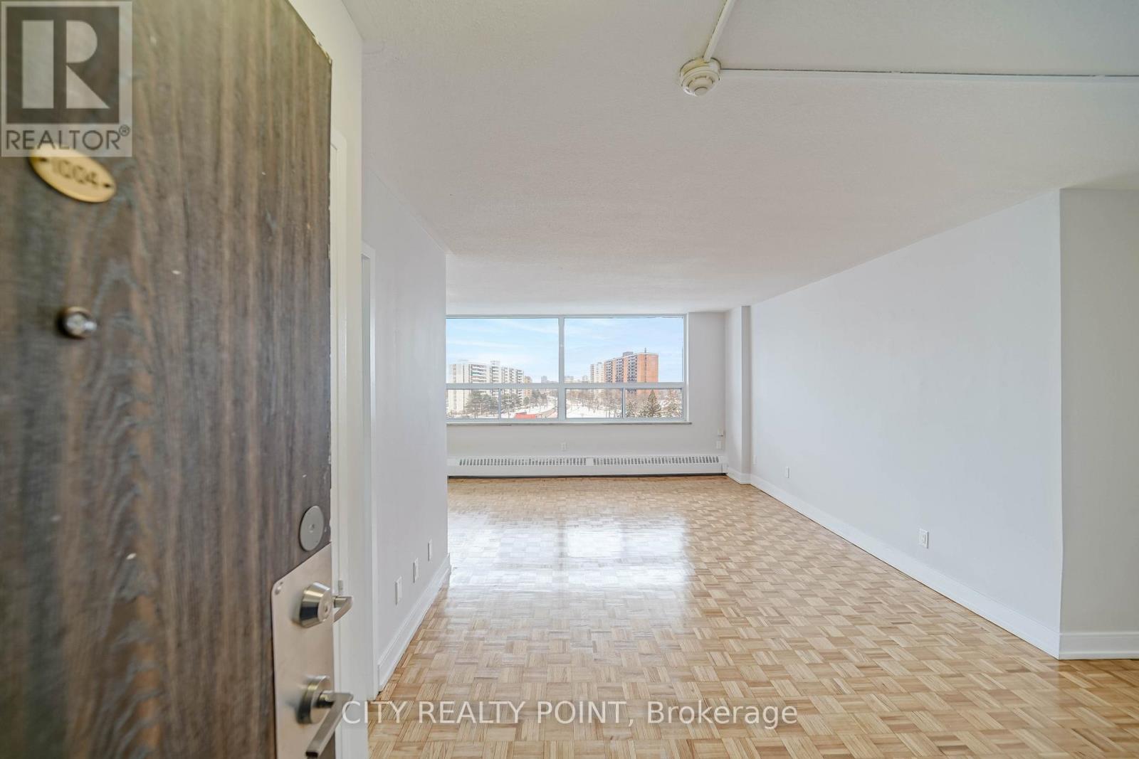 A room with a wooden door and a window overlooking a cityscape.