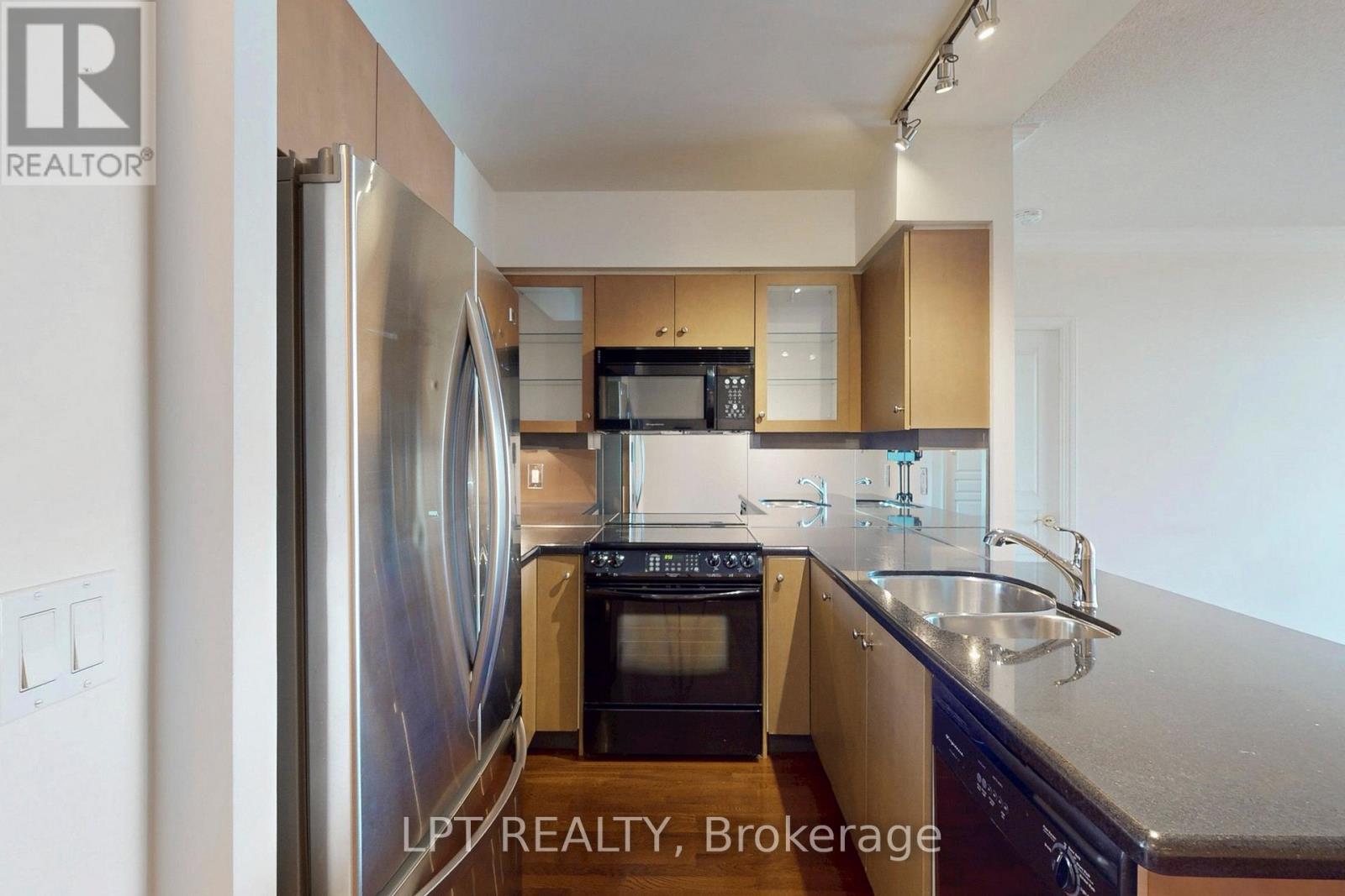 A kitchen with a refrigerator, microwave, oven, and sink.