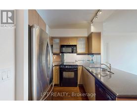 A kitchen with a refrigerator, microwave, oven, and sink.