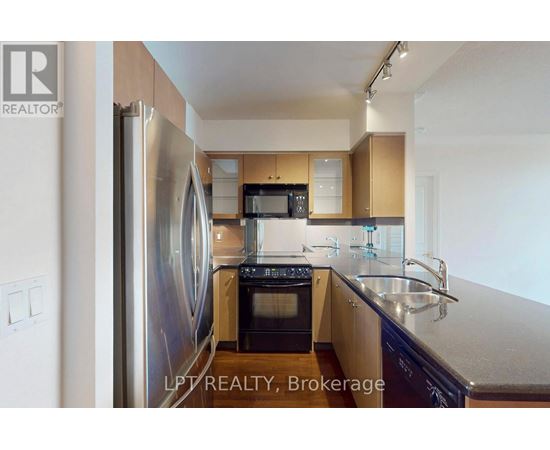A kitchen with a refrigerator, microwave, oven, and sink.