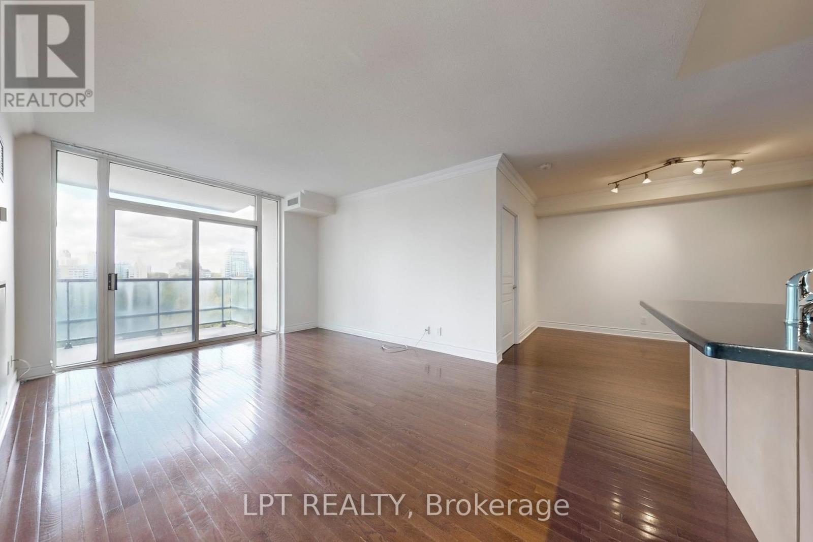 A spacious room with wooden flooring and a large window.