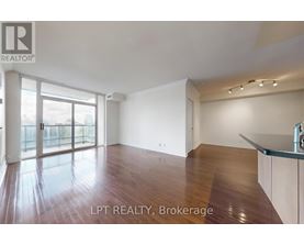 A spacious room with wooden flooring and a large window.