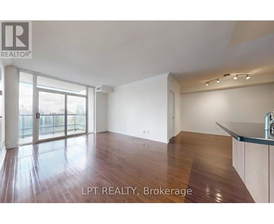 A spacious room with wooden flooring and a large window.