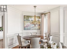 A dining room with a chandelier, a table with chairs, and a painting on the wall.