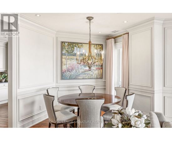 A dining room with a chandelier, a table with chairs, and a painting on the wall.