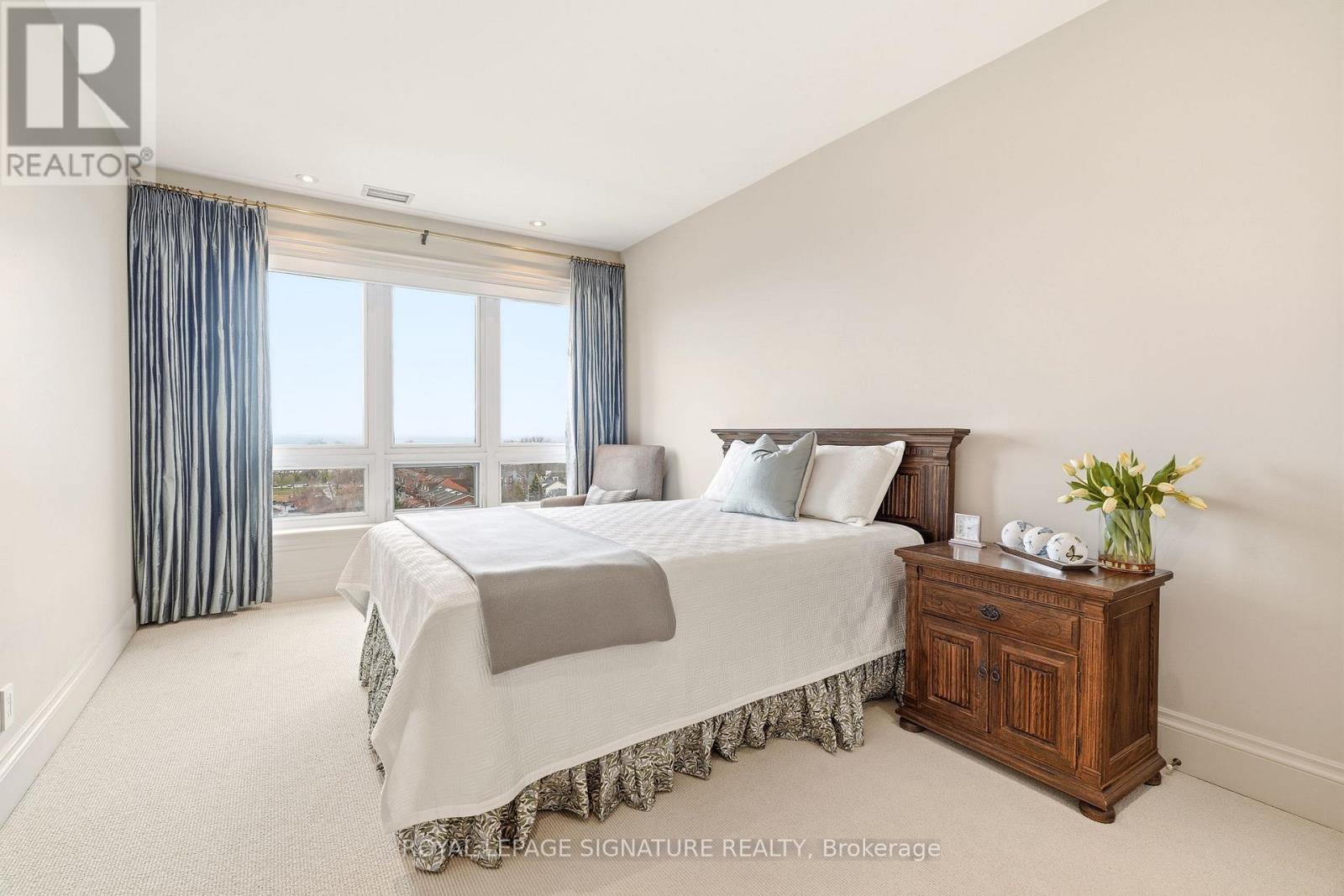 A bedroom with a large bed and a wooden cabinet.
