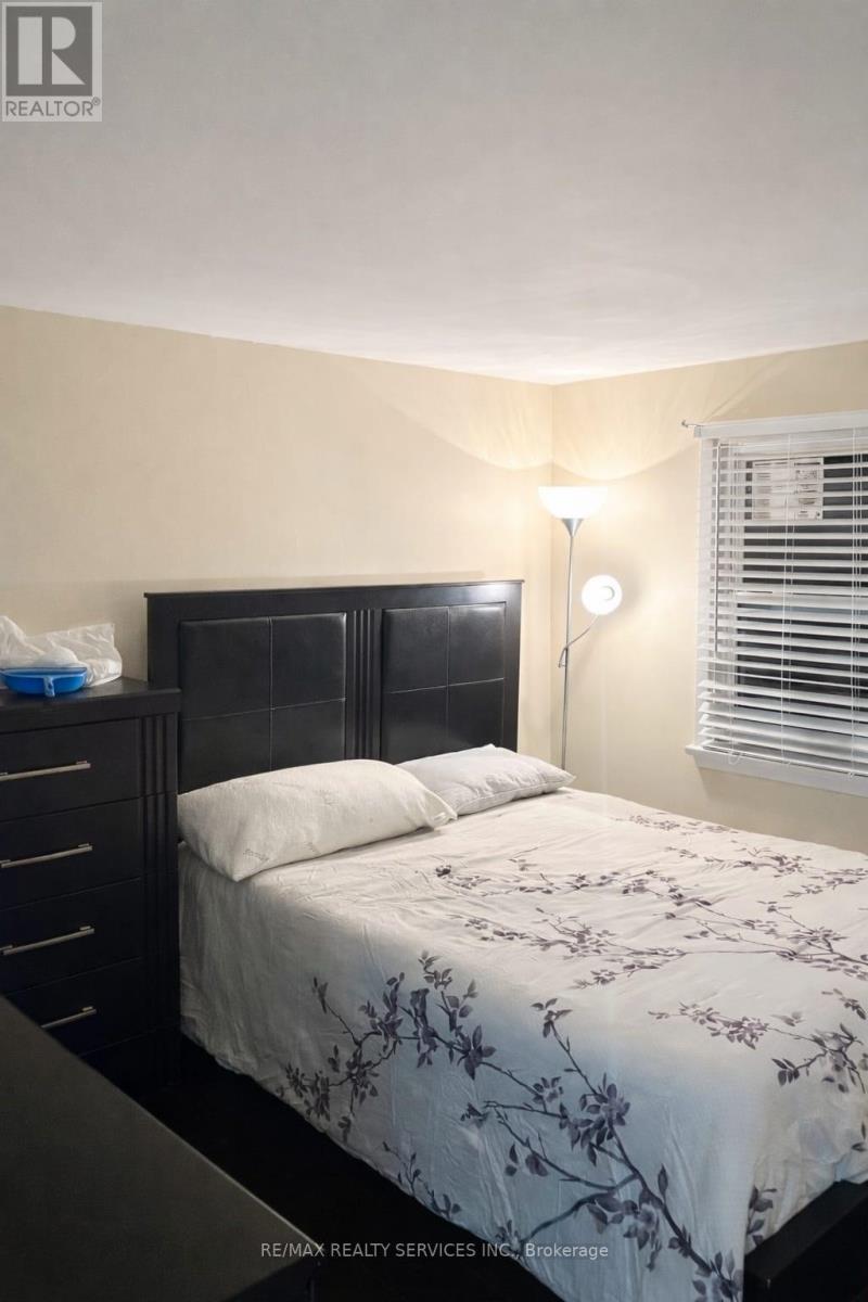 A bedroom with a bed, nightstand, and window with blinds.