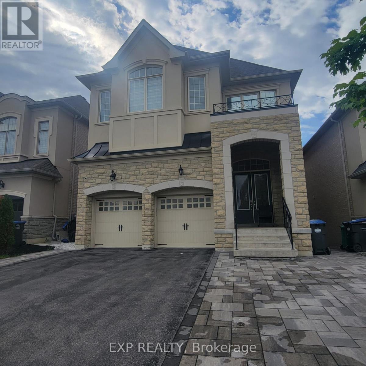 A large house with a stone entrance and two garages is for sale.