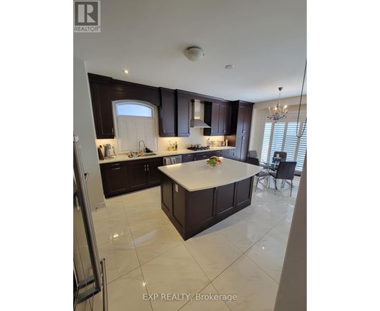 A kitchen with dark brown cabinets and a white island.