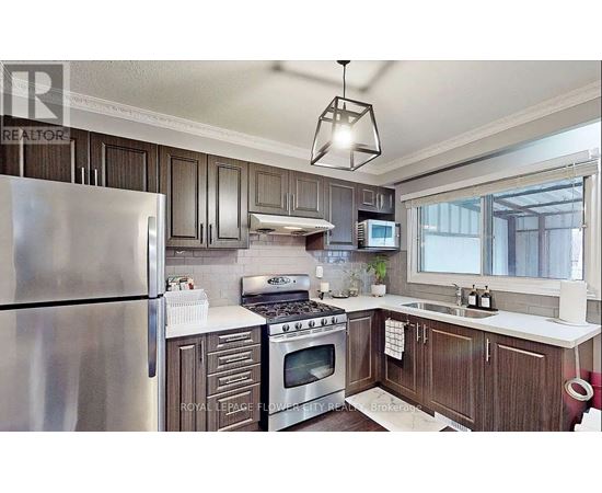 A kitchen with a stainless steel refrigerator and wooden cabinets.