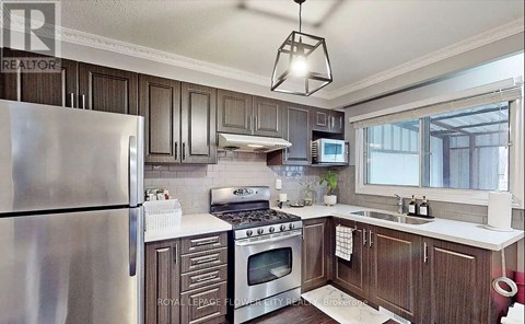 A kitchen with a stainless steel refrigerator and wooden cabinets.